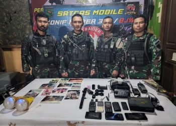 Satgas Pamtas Mobile Yonif Raider 300/Bjw saat mempelihatkan barang sitaan milik KKB