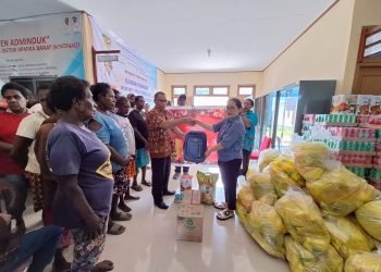 Bendahara GOW Kabupaten Mimika Ny. Herlina Pongdatu saat menyerahkan bantuan kepada Kepala Distrik Mimika Barat Christian Warinussy di Kampung Kokonao